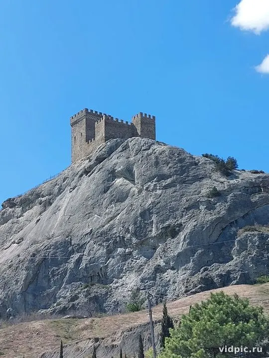 A medieval castle situated atop a cliff. The architecture and surroundings evoke a sense of historical significance.
