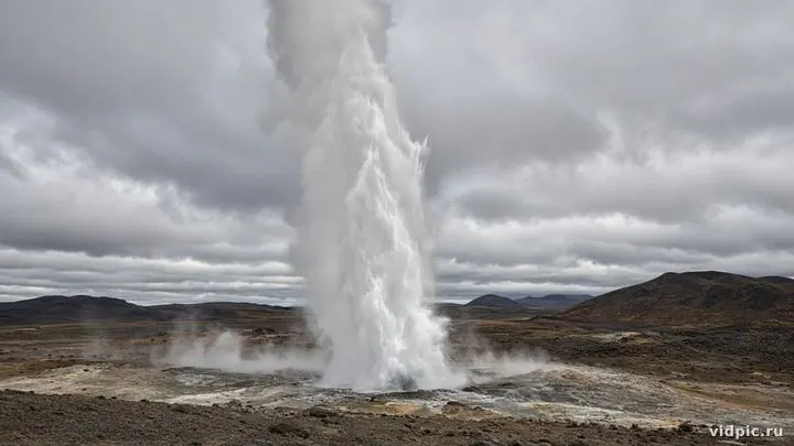 A column of steam and water over volcanic terrain.