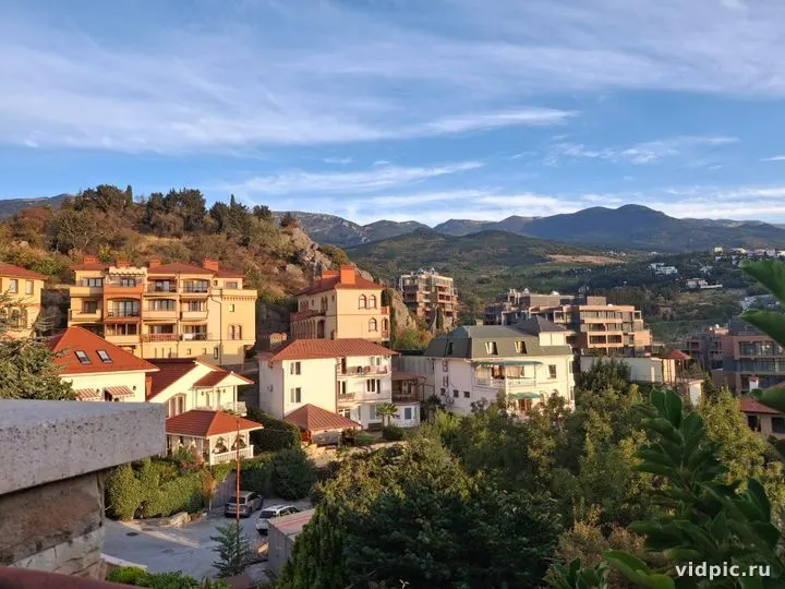 A city at the foot of mountains with a view of residential buildings and green plantations. Suitable for illustrating urban life in a mountainous area.