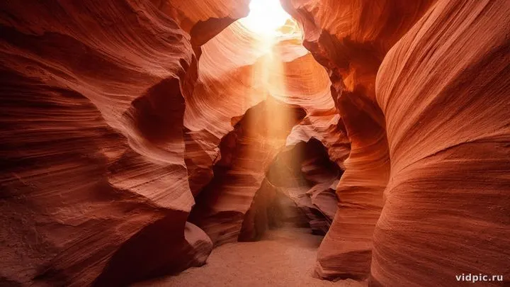 Orange sandstone waves with light beams from above.