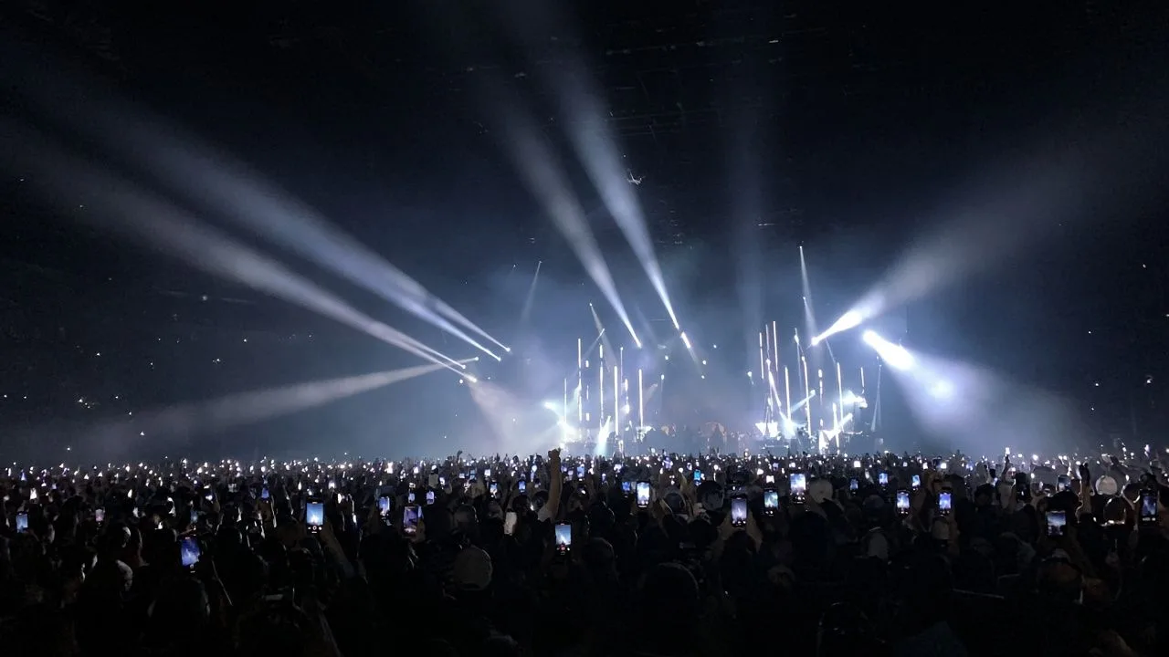 Concert lights. A sea of phone lights and stage beams.