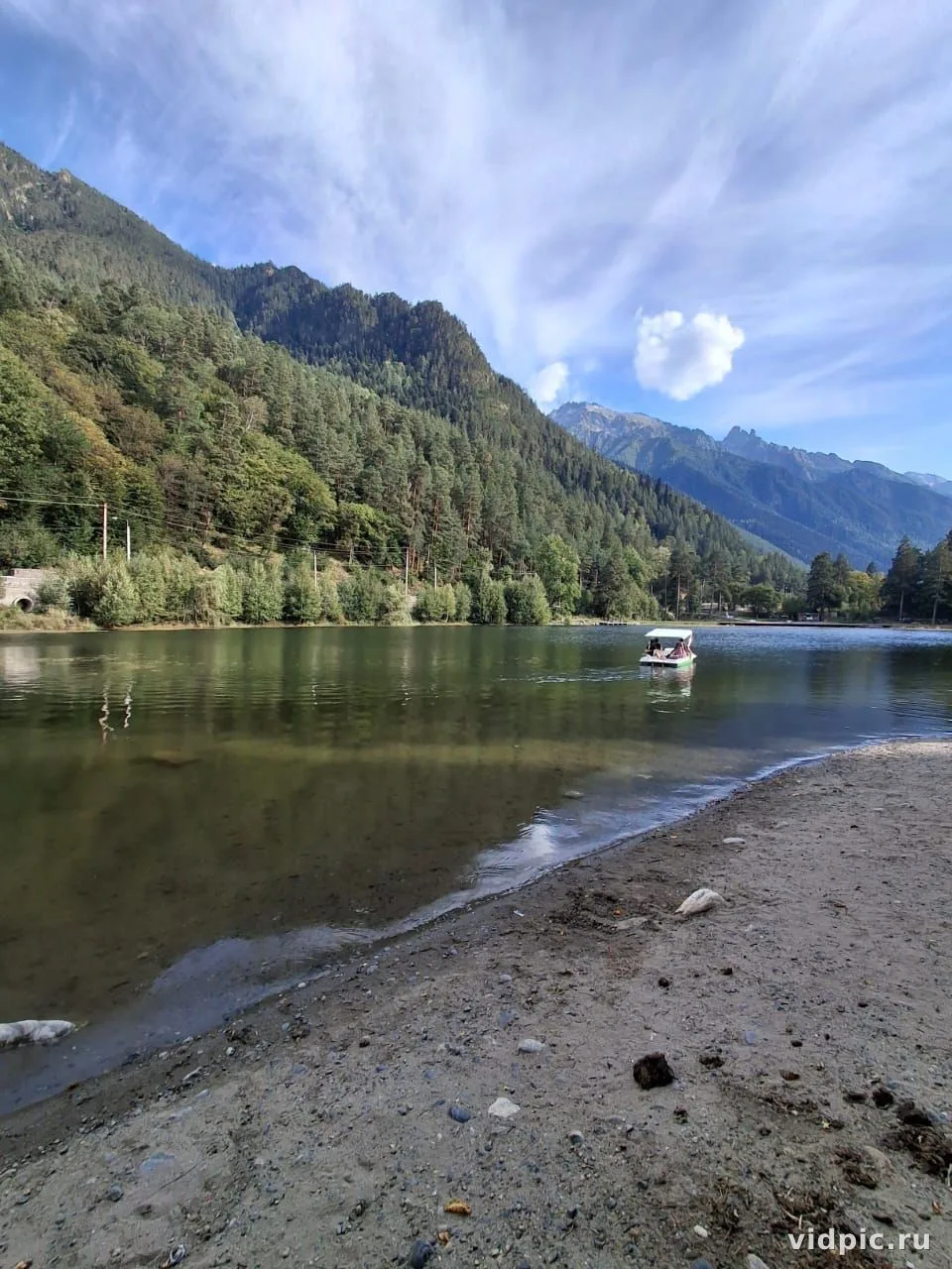 Lake at the foot of the mountains. A tranquil lake at the foot of the mountains, surrounded by green forests.
