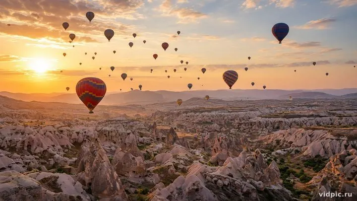 Colorful balloons over rock formations at sunrise.